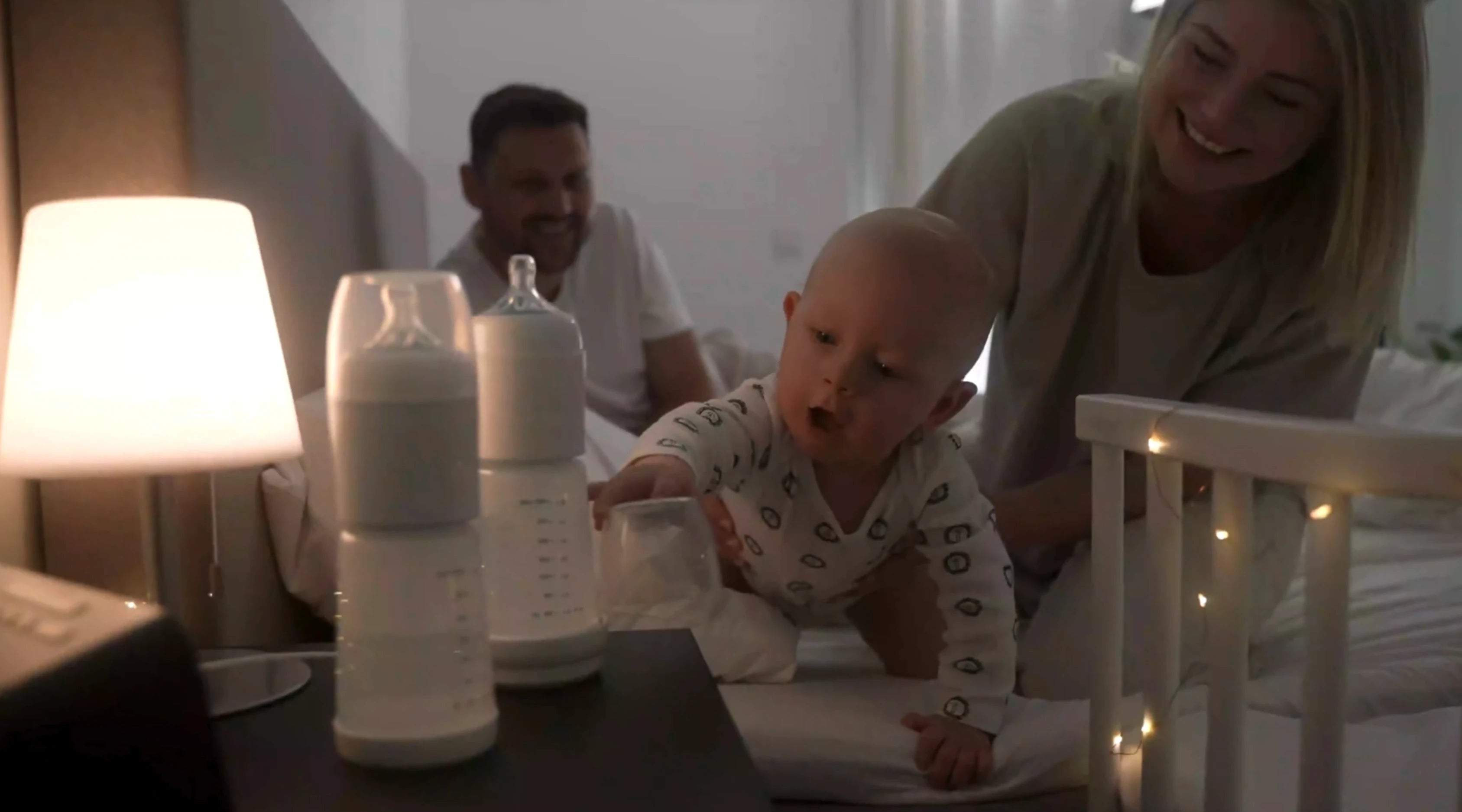 Bébé veut prendre le biberon snoozi et les parents l'aident